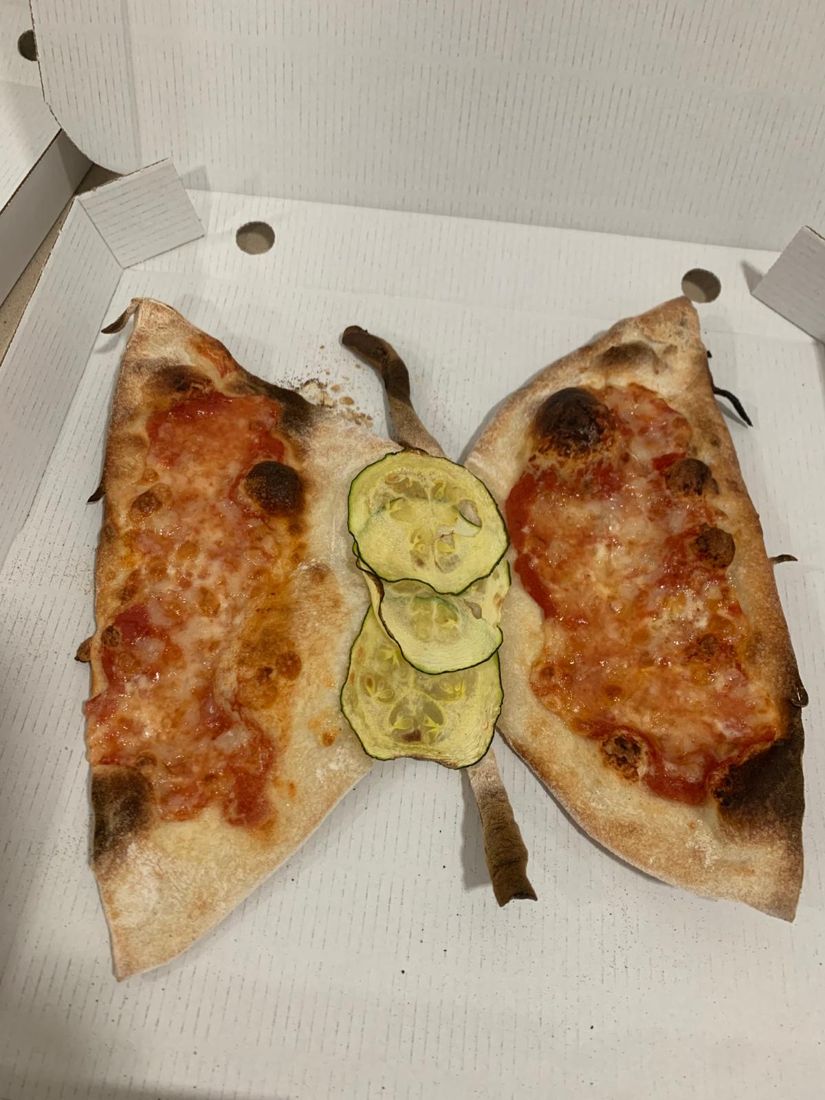 Pizza cortada con forma de mariposa, con rodajas de calabacín en el centro