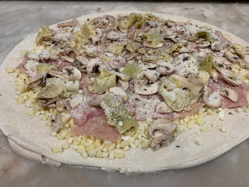 Base de pizza con jamón, champiñón y alcachofa antes de hornear