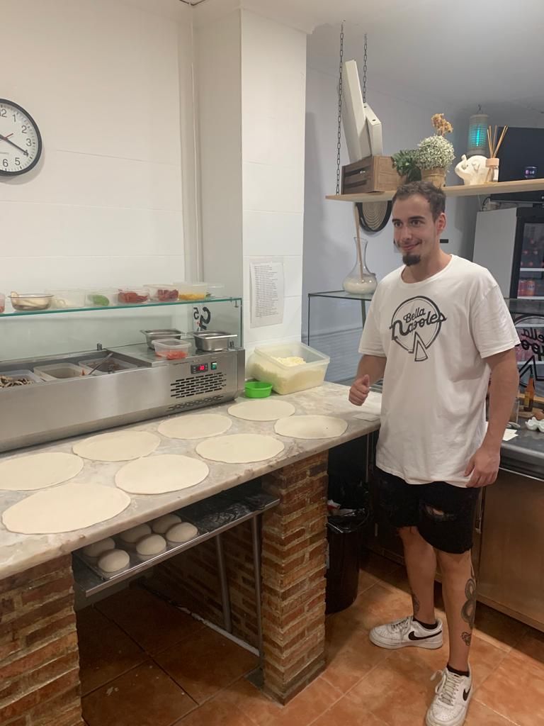El pizzero sonriendo en el obrador junto a la mesa de trabajo